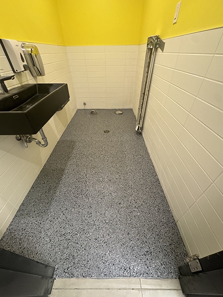 Plancher époxy à granules gris pour salle de bain commerciale, revêtement antidérapant, réalisation VirezSulTop Époxy Design chez Allô mon Coco à Laval.