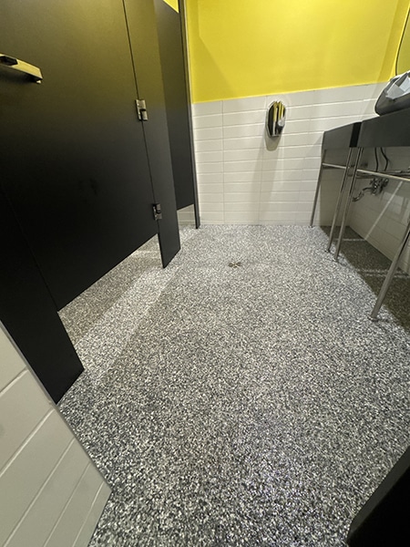 Plancher époxy à granules gris pour salle de bain commerciale, revêtement antidérapant, réalisation VirezSulTop Époxy Design chez Allô mon Coco à Laval.