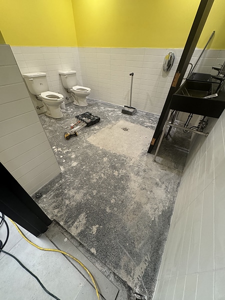 Plancher commercial avant réfection en époxy, salle de bain avec surface abîmée, projet Allô mon Coco par VirezSulTop Époxy Design à Laval.